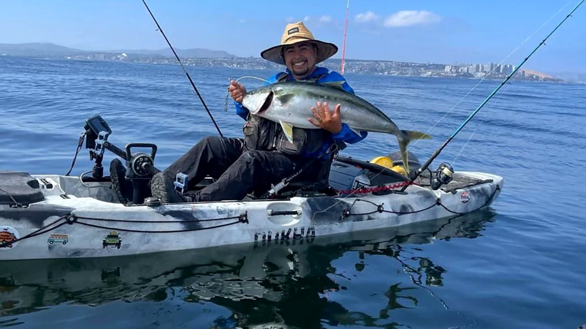 Pescador con una vidriola sentado en su kayak de pesca Dukha en el mar